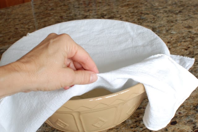 White cloth covering rising dough in large bowl