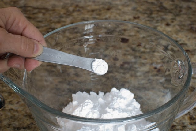 powdered sugar in a clear bowl adding cream of tartar