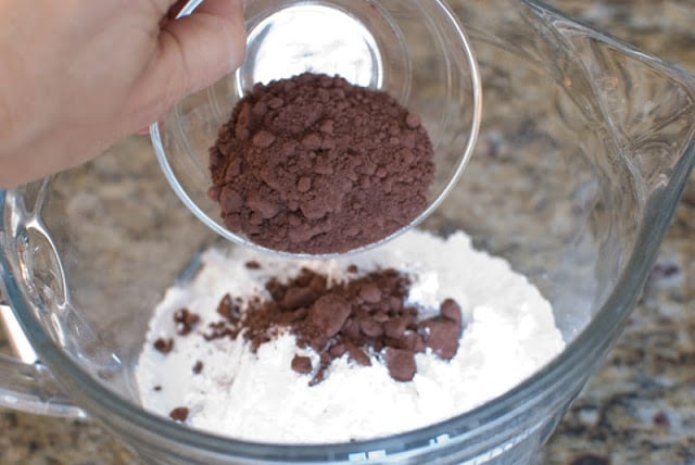 Clear bowl with powdered sugar and cocoa being added