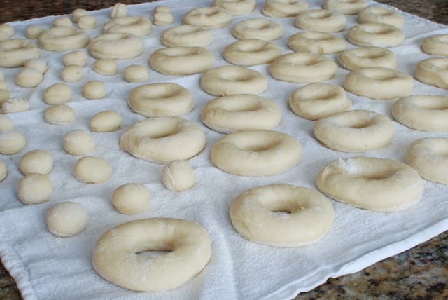 Several cut spudnuts and donut holes on white floured cloth