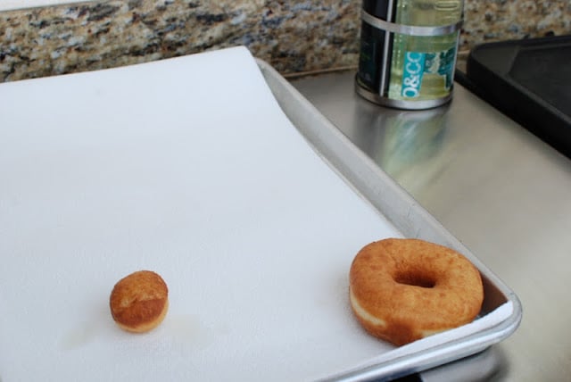 Baking sheet lined with a paper towel with a spudnut and donut hole draining
