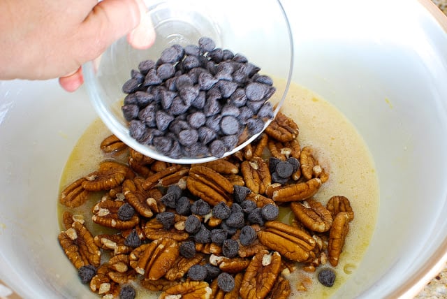 adding pecans and chocolate chips to pie mixture