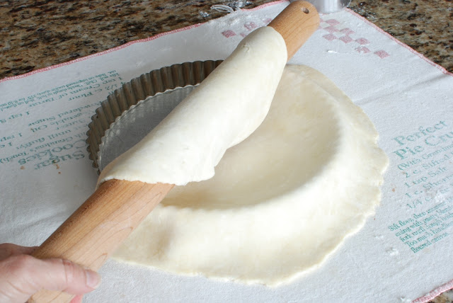 Rolling pie dough over tart tin