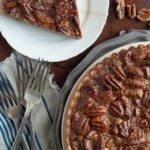 overhead shot of pecan chocolate tart with slice on a plate