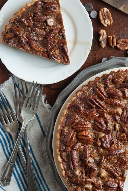 overhead shot of pecan chocolate tart with slice on a plate