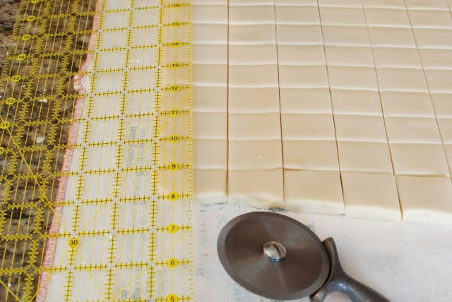 large ruler and pizza wheel cutting shortbread dough into squares