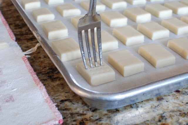Cut shortbread cookies on a baking sheet docking with a fork