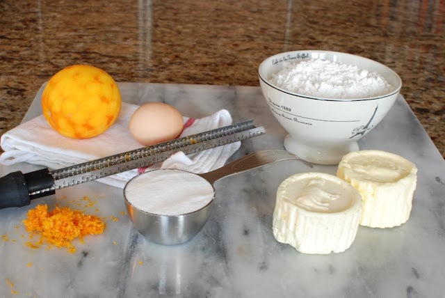 Butter, orange, egg, sugar, flour on marble board