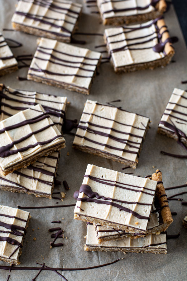Peanut butter bars stacked and scattered on a sheet of parchment