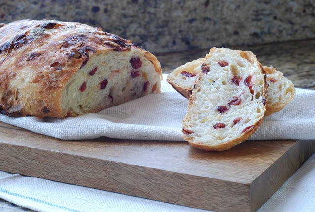 sliced orange cranberry bread on cutting board with 2 slices