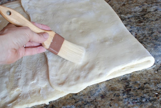 Pastry brushing off excess flour from butterflake dough.