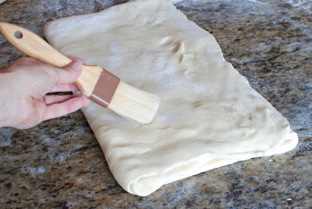 Pastry brushing off excess flour from dough