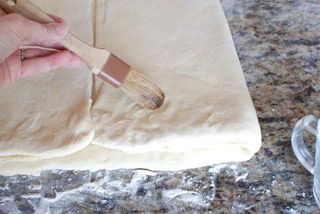 Brushing folded dough with water.
