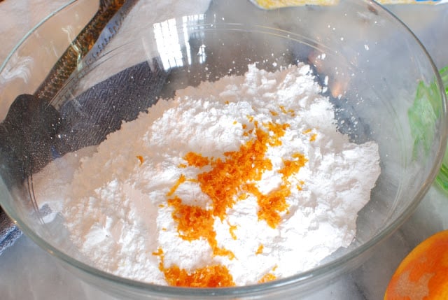 Powdered sugar and orange zest in a mixing bowl.