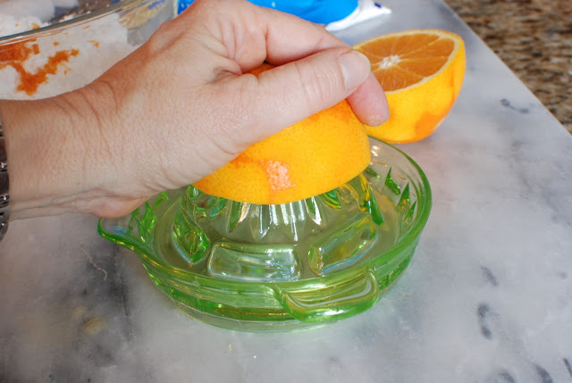 Hand juicing an orange half.