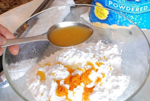 Adding orange juice to powdered sugar to make the butterflake roll glaze.