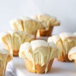 Several orange glazed butterflake rolls on a white marble tray.