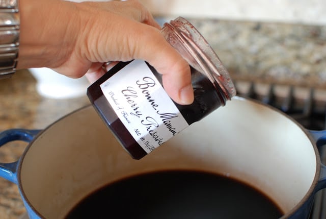 Cherry preserves added to cherry cola in pot.