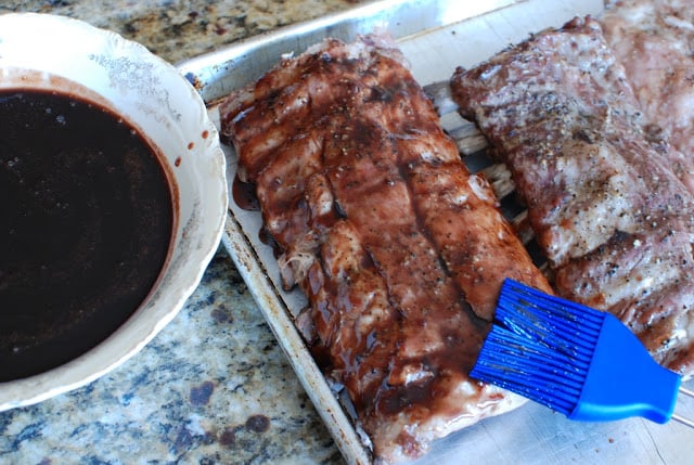 Baked ribs on a baking sheet glazed with cherry cola sauce.