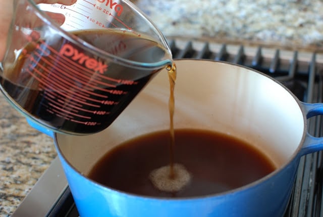 Cherry cola pouring into a blue pot.