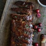 Glazed ribs on a wood board with cherries along the side