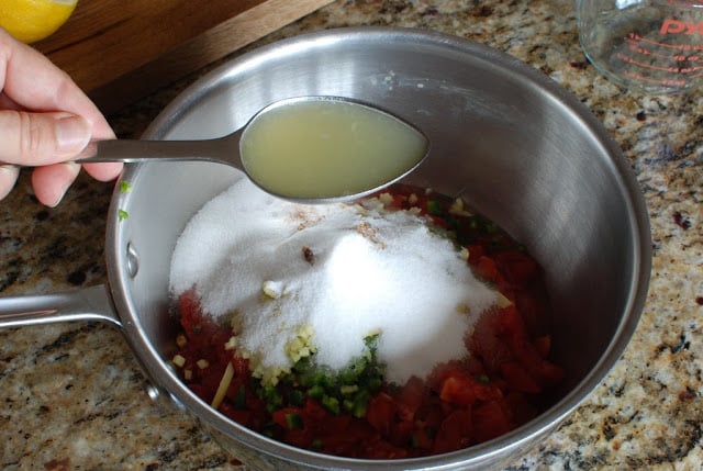 spoonful of lemon juice added to tomato mixture in saucepan