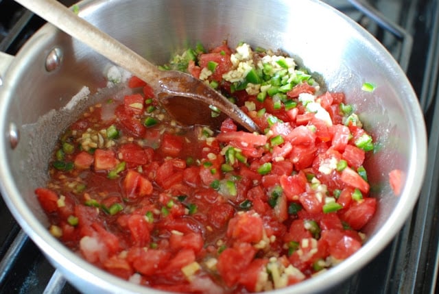 tomato jam ingredients in saucepan with wooden spoon mixing