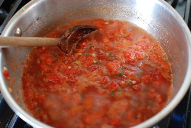 simmering tomato jam with wooden spoon stirring