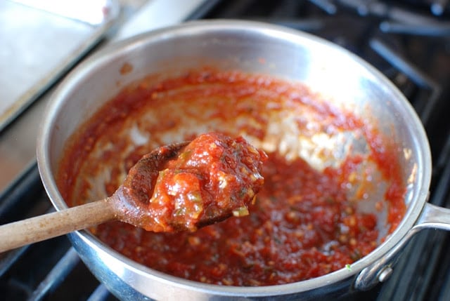 thickened tomato jam in saucepan and wooden spoon