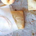 hand peach pie in a glassine bag on baking sheet with red and white twine