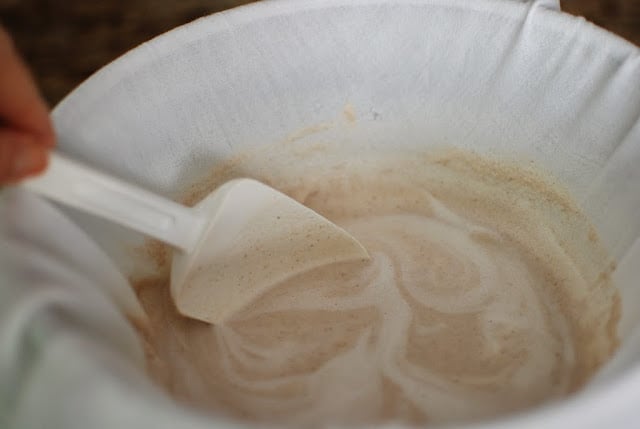 white rubber spatula stirring almond milk and pulp