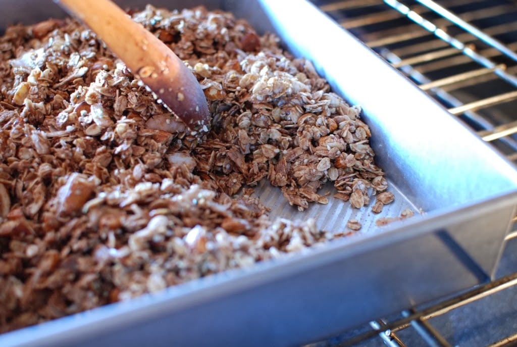 Baked granola stirred with wooden spoon