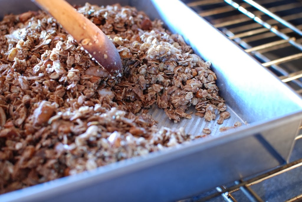 Baked granola stirred with wooden spoon