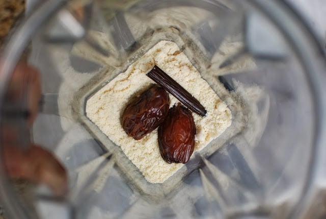 overhead shot of blender with water, almond flour, 2 dates and 1/2 vanilla bean