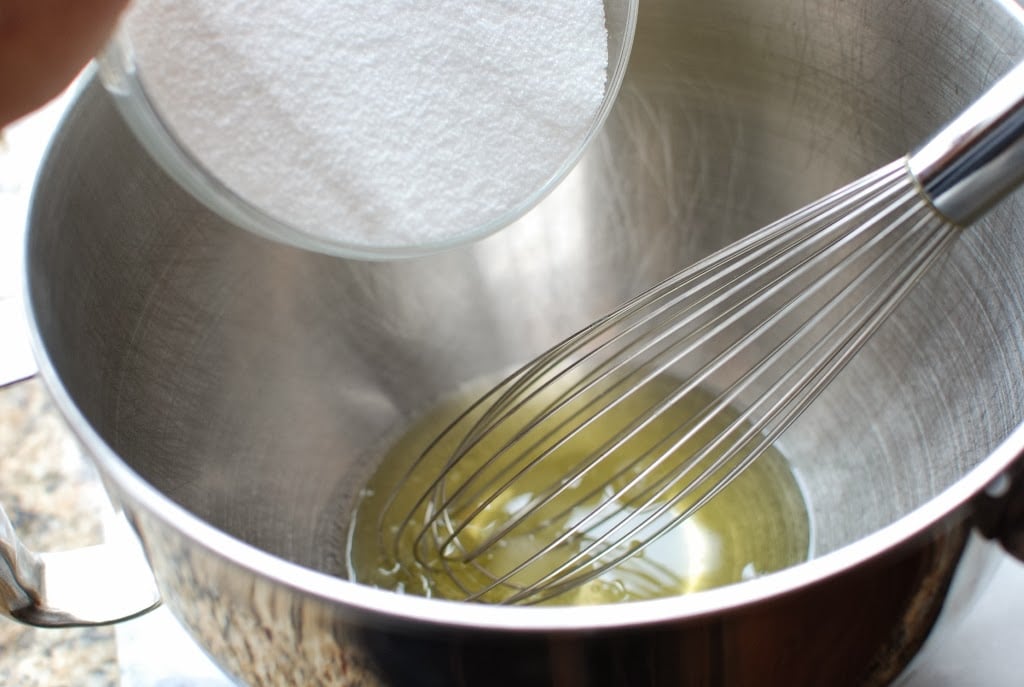 egg whites with sugar pouring into bowl and wire whisk