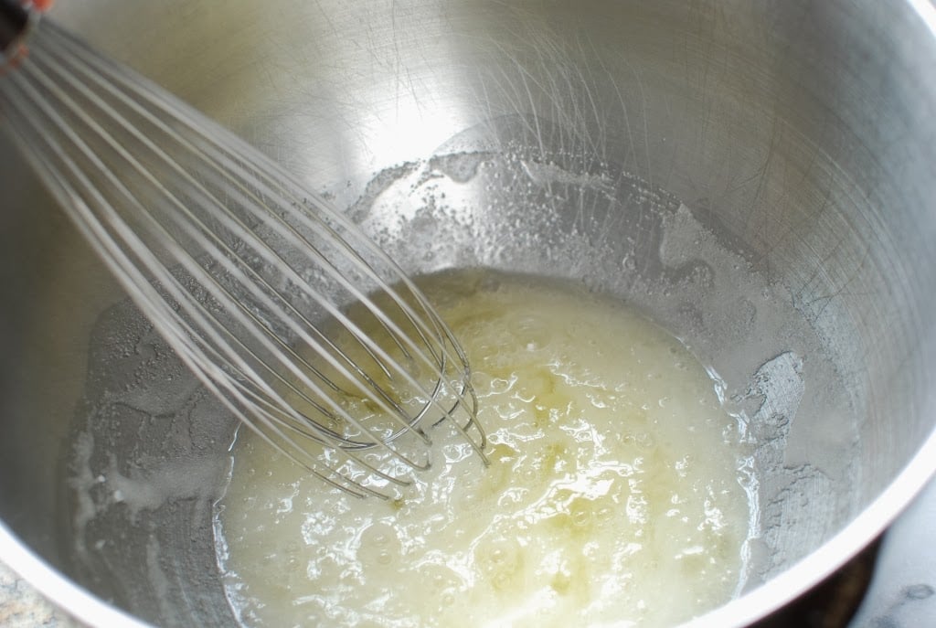 Wire whisk mixing sugar and egg whites in bowl of mixer