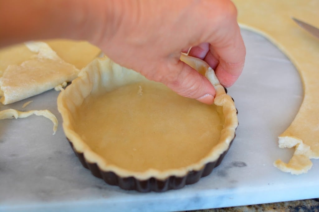 Pressing pie dough into tart tin