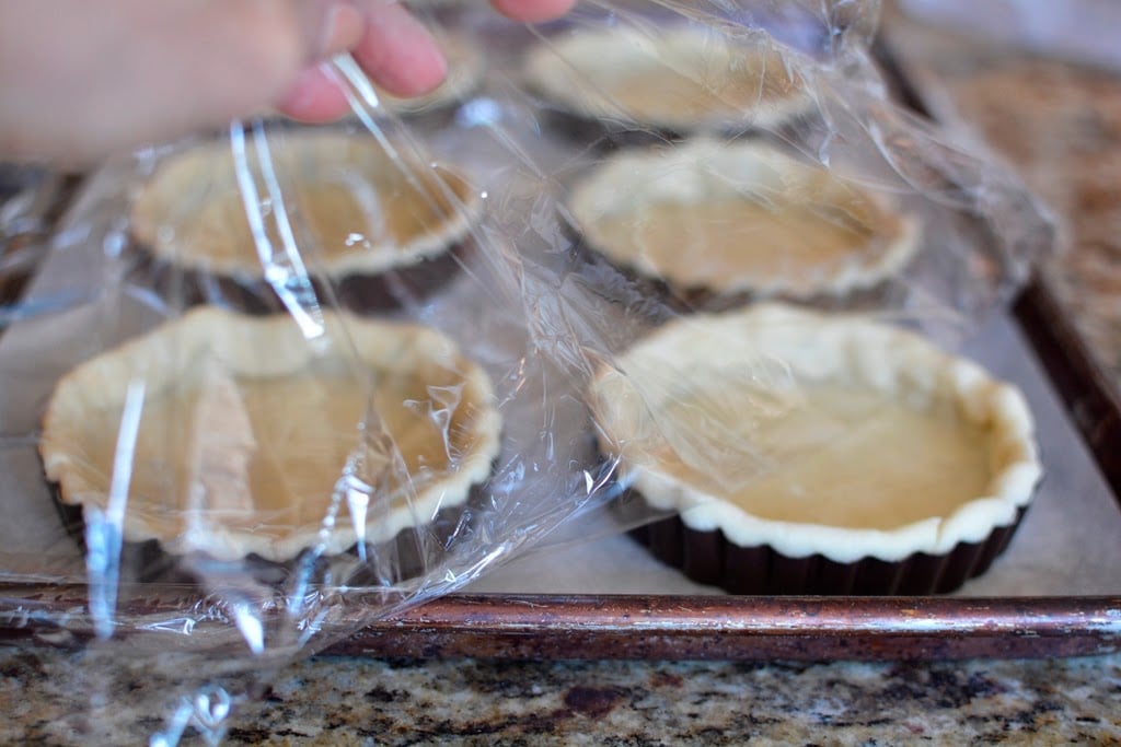 6 tarts on baking sheet covered with plastic wrap