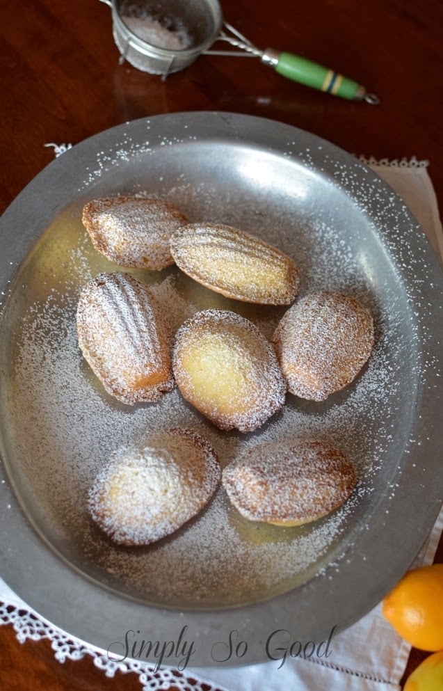 Madeleines on a metal plate sprinkled with powdered sugar