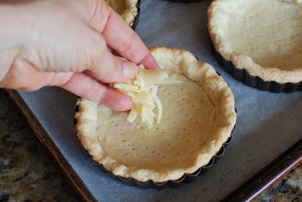 adding grated cheese to quiche shell