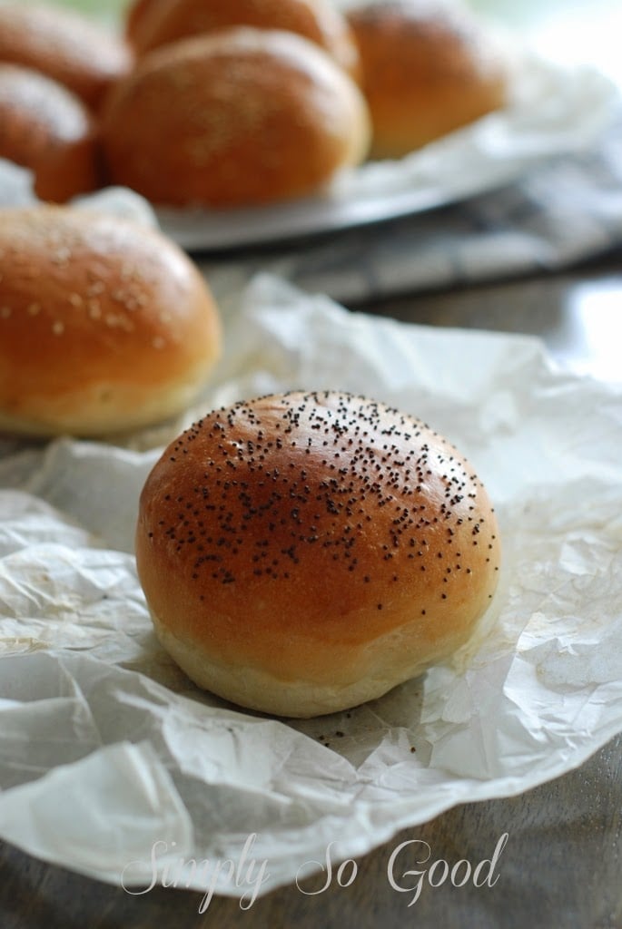 Brioche burger buns sprinkled with poppy seeds on sheet of parchment