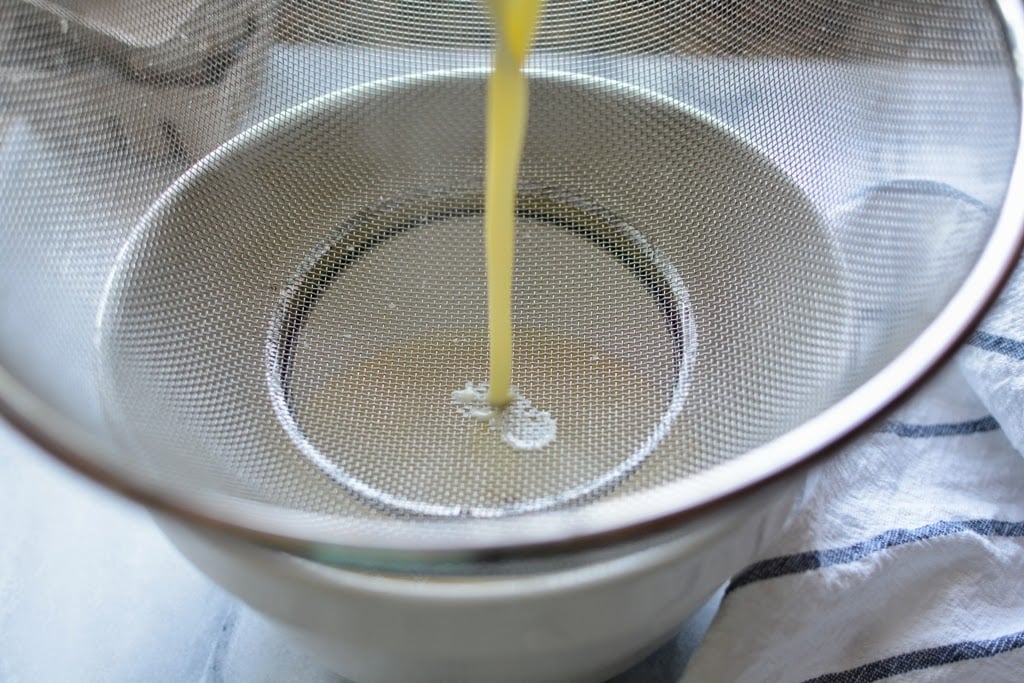 ice cream mixture pouring through a wire mesh strainer into a bowl
