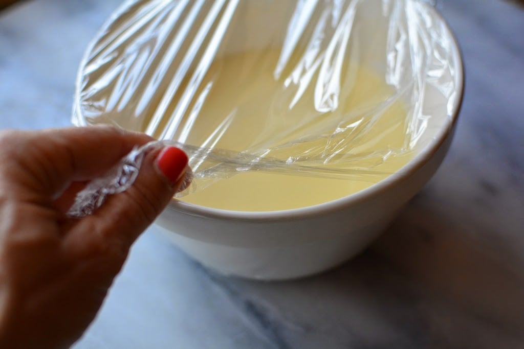 Ice cream mixture in a white bowl covered with plastic wrap