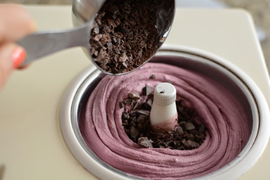 Chopped chocolate added to churned blackberry ice cream