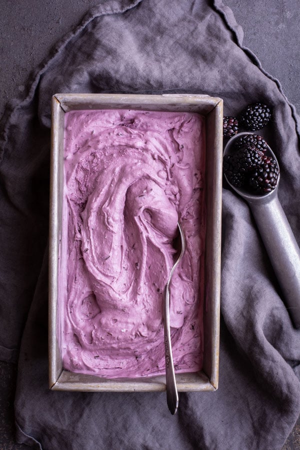 rectangular bread pan with ice cream on dark gray cloth with Blackberry Chocolate Chip ice cream scoop and blackberries