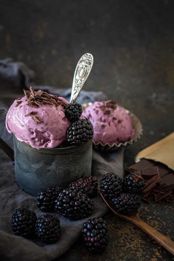 front view of Blackberry Chocolate Chip Ice cream in dark tin mug with blackberries, chopped chocolate