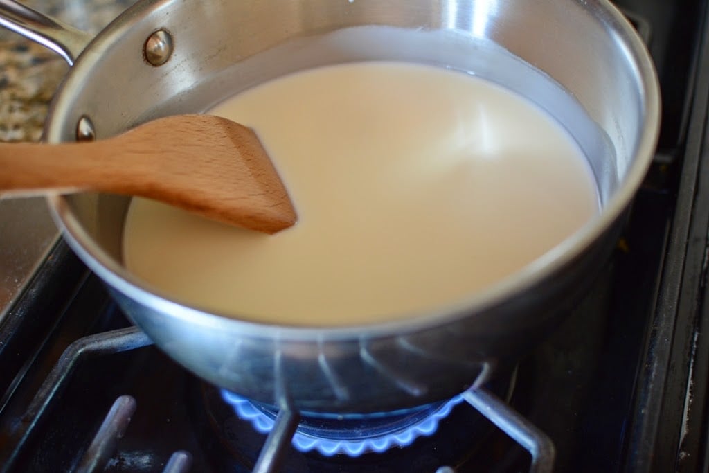 Sauce pan with cream, milk, sugar, salt mixture stirring with wood spoon