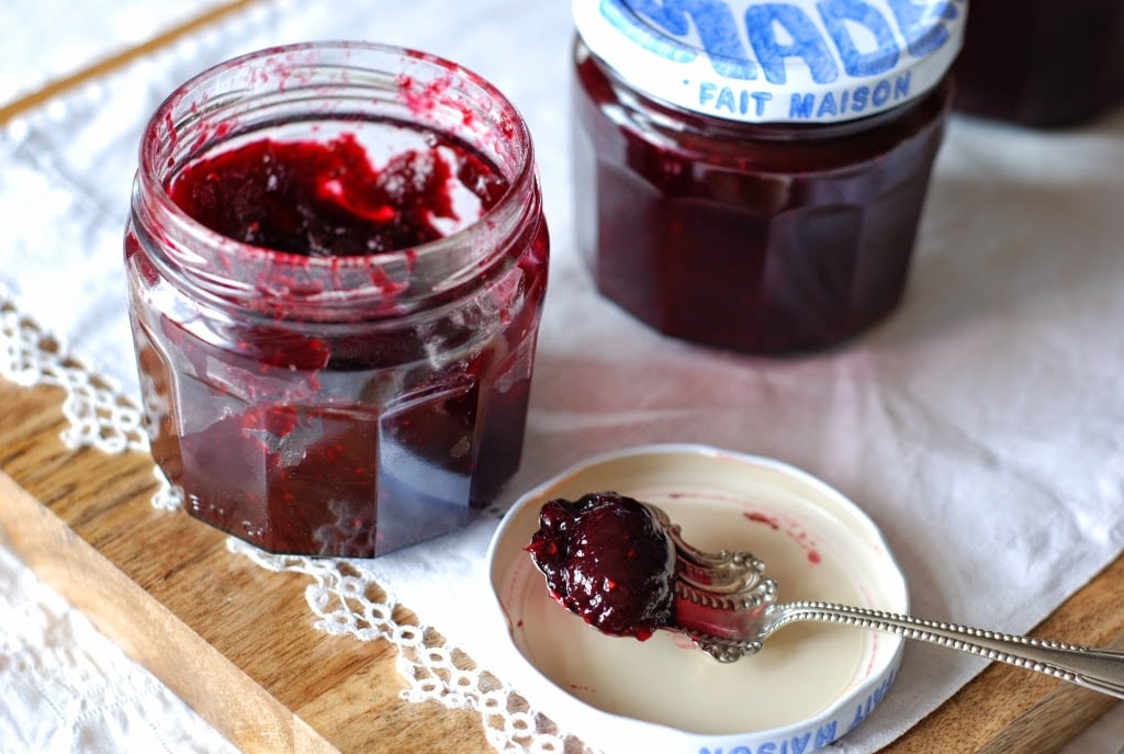 Two jars of blackberry raspberry jam with spoonful on a lid