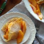 white plate with crepe filled with peaches