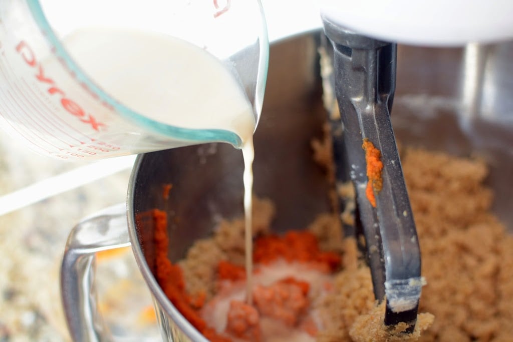 milk pouring into pumpkin mixture added to flour mixture in mixing bowl